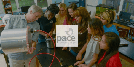 Photo with PACE logo: PACE students gather to watch science teacher conduct an experiment.