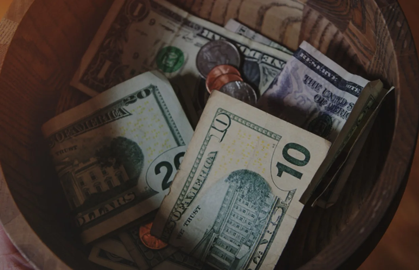 Photo: Cash and coins placed in a wooden donation bowl.